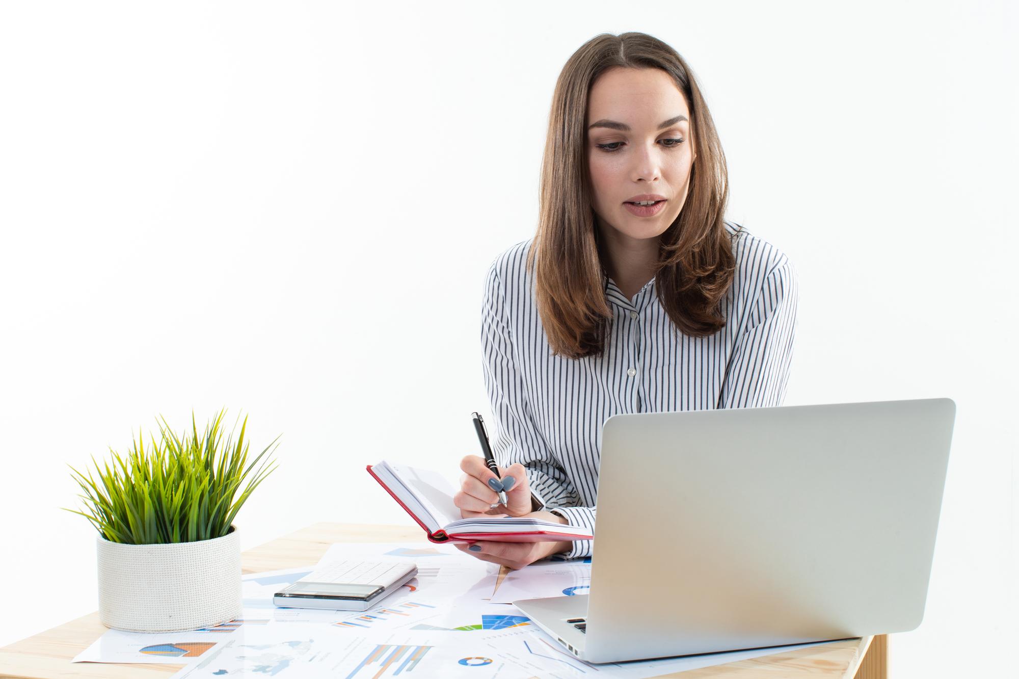 Person arbeitet mit Budgetplan auf Laptop in hellem Workspace